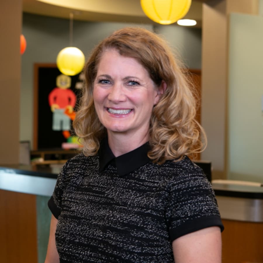 A smiling portrait of Dr. Lyons in the reception area of North Seattle Orthodontics